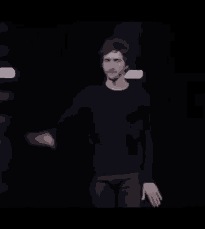 a man in a black shirt is dancing on a stage in the dark .