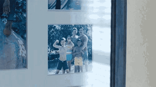a framed photo of a family standing next to each other in front of a window .