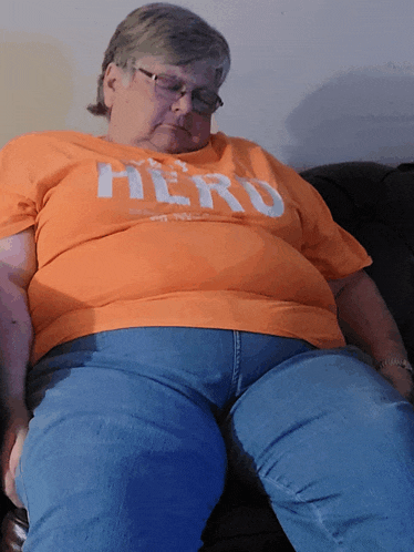 an older woman wearing an orange shirt that says hero