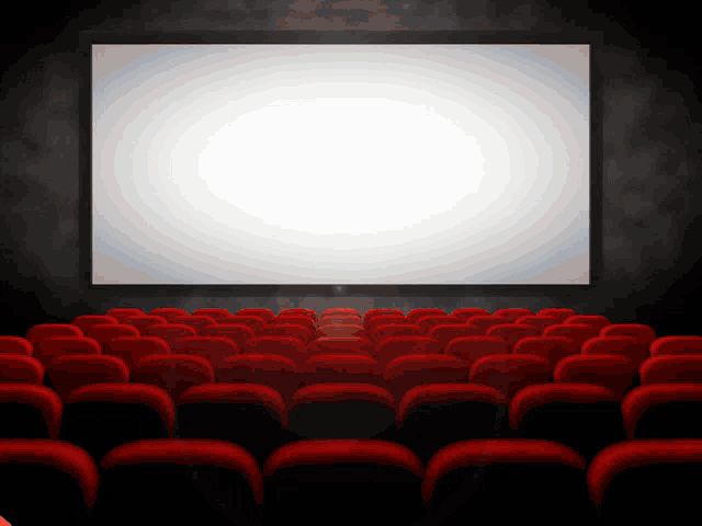 an empty movie theater with red seats and a large white screen