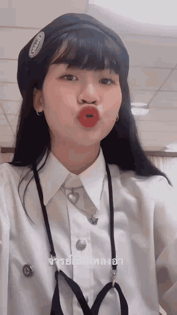 a girl wearing a beret and a white shirt is making a kissing face