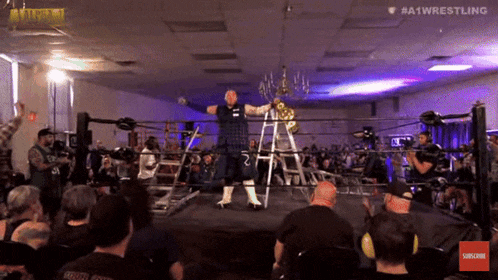 a man in a kilt is holding a trophy in a wrestling ring with #a1wrestling in the corner