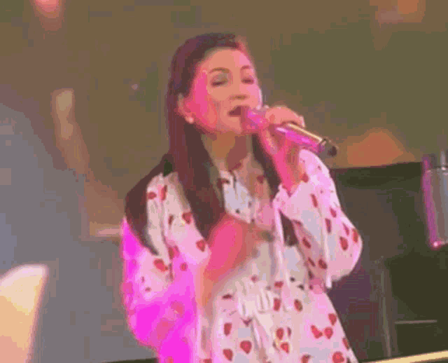 a woman singing into a microphone while wearing a strawberry dress