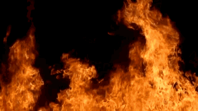a large fire is burning in the dark on a black background .