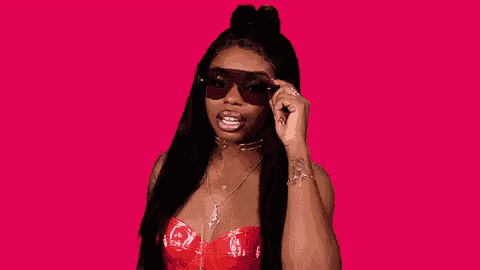a woman wearing sunglasses and a red top is looking at the camera .