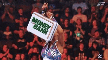 a wrestler is holding a briefcase over her head in front of a crowd .