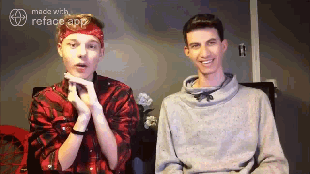 two young men are sitting next to each other in front of a computer screen .