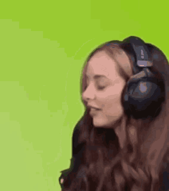 a woman wearing headphones is making a funny face on a green background .