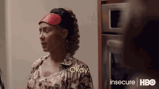 a woman wearing a red eye mask says okay in a kitchen .