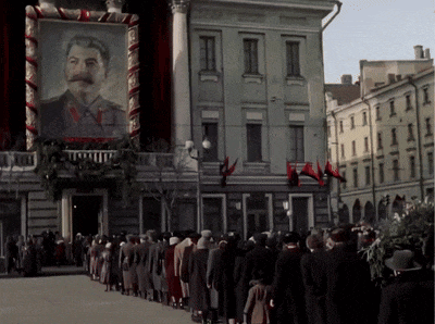 a group of people standing in front of a building with a picture of a man