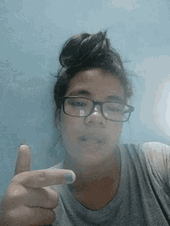 a girl wearing glasses giving a thumbs up
