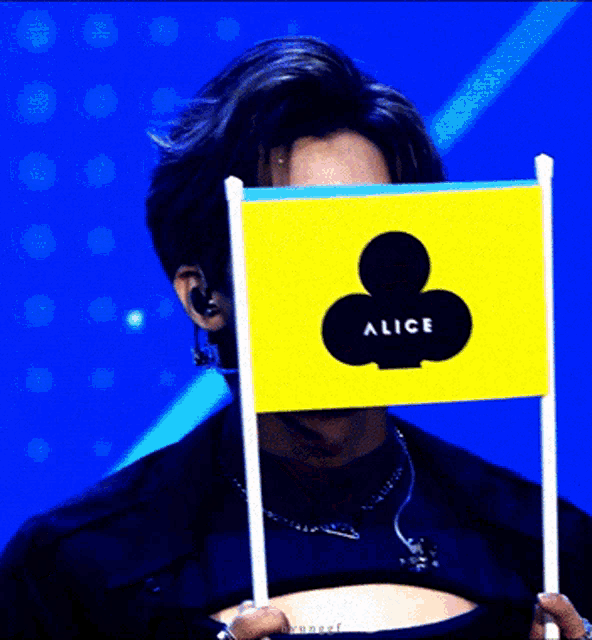 a person holding a small yellow flag with a playing card on it that says alice