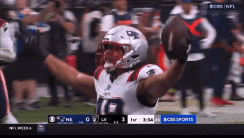 a patriots football player is holding a football in his hands