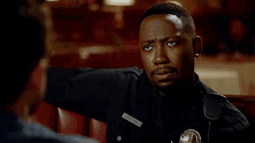 a police officer is talking to another man in a diner while wearing a badge that says ' officer '