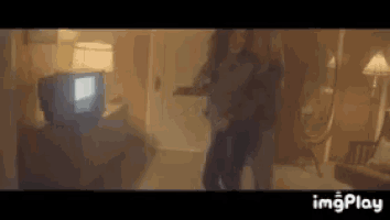 two women are dancing in a room with a television and a mirror