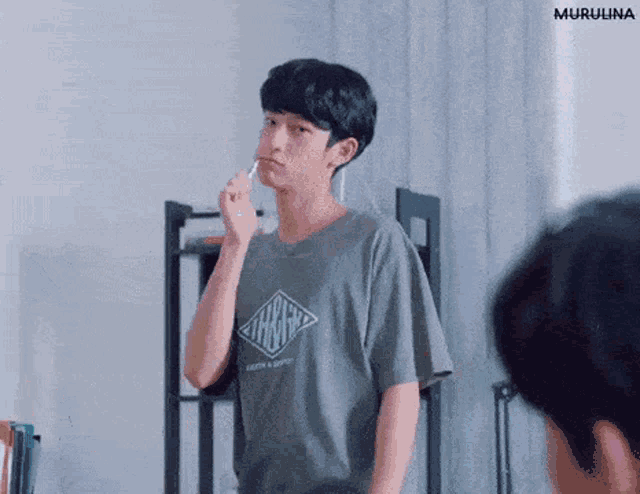 a young man is brushing his teeth with a toothbrush in a living room .