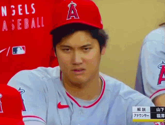 a baseball player wearing a red hat that says angels on it