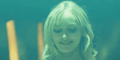 a woman with her arms in the air is dancing in a dark room .