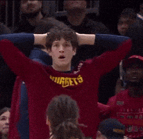 a man wearing a red nuggets jersey with his hands on his head