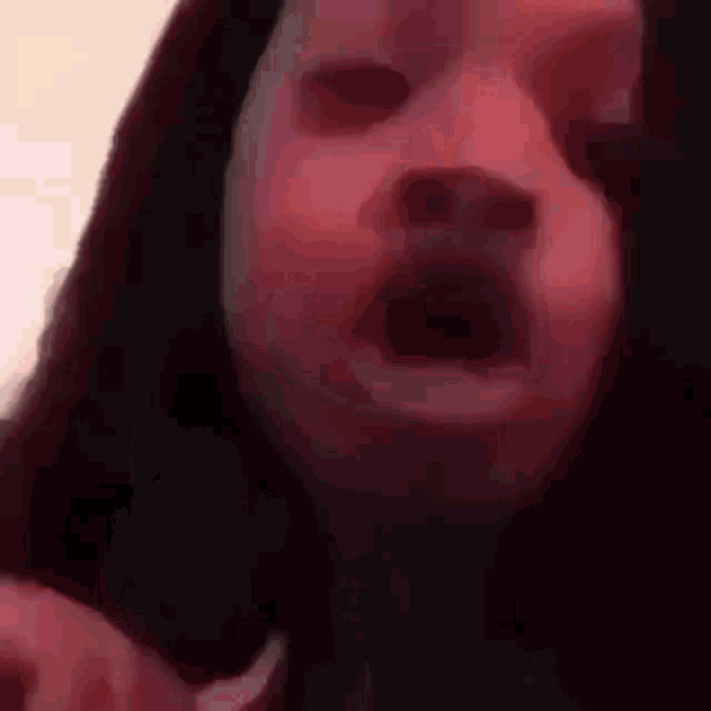 a woman with long black hair is making a funny face in a blurry video .
