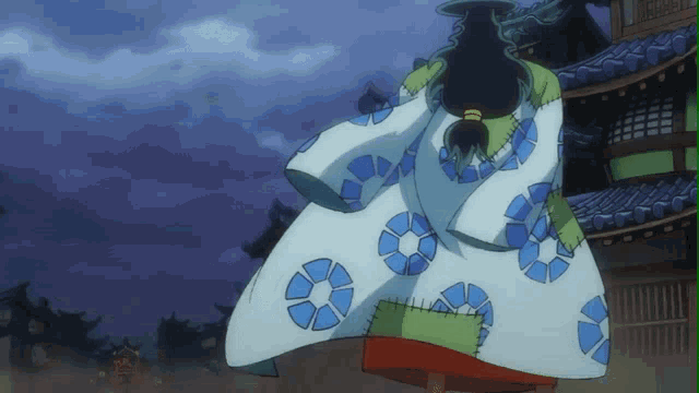 a person in a kimono with blue circles on it stands in front of a building