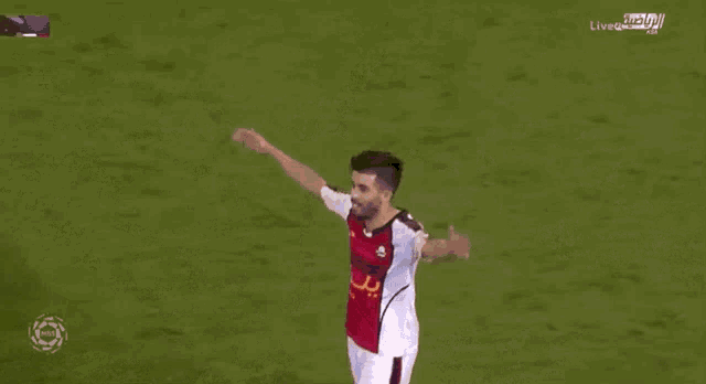 a soccer player wearing a red and white jersey with the letter b on it is covering his face