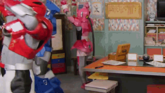 two robots are standing next to each other in a room next to a table .