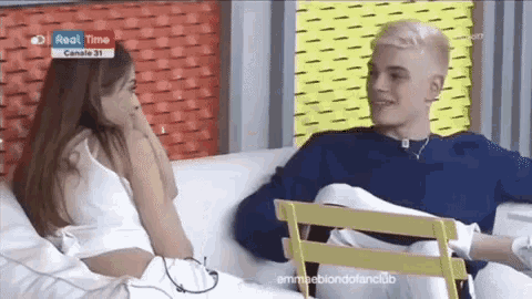 a man and a woman are sitting on a couch and talking to each other ..