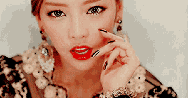 a close up of a woman 's face with red lips and black nail polish