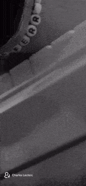 a black and white photo of a person wearing a bracelet with the name charles leclerc at the bottom