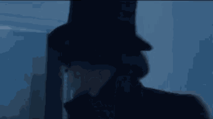 a man wearing a top hat and a red coat is standing in front of a window in a dark room .