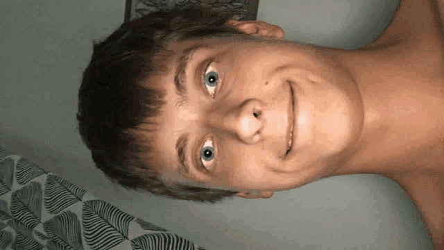 a young man without a shirt is smiling and looking at the camera