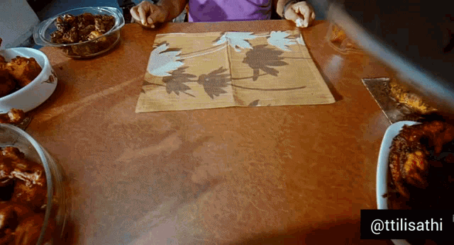 a person sitting at a table with plates of food and a napkin that says @tillisathi