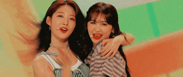 two young women are hugging each other on a colorful background and smiling .