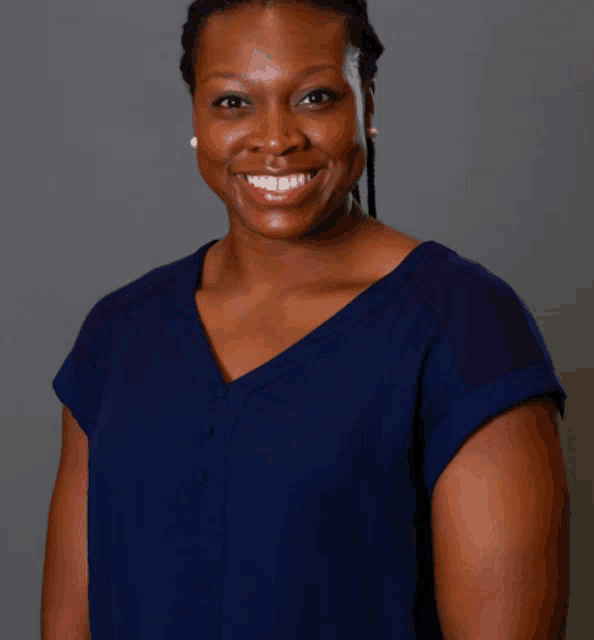 a woman wearing a blue shirt is smiling and looking at the camera