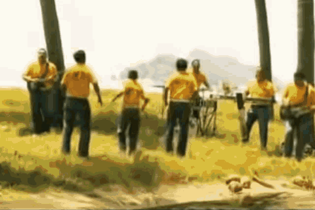 a group of people in yellow shirts are standing in a field