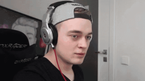 a young man wearing headphones and a hat is making a funny face .