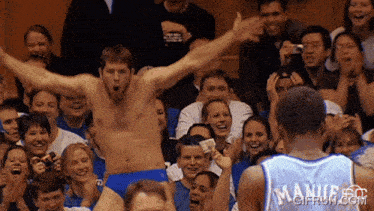 a man without a shirt is standing in front of a crowd with a man wearing a jersey that says " manifest " on it