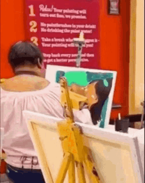 a woman is sitting at an easel painting a picture of a woman .