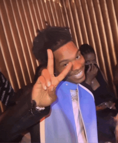a young man giving a peace sign with his fingers