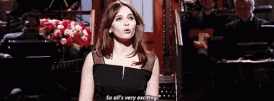 a woman in a black dress says " so all 's very exciting " in front of an orchestra