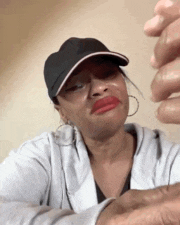 a woman wearing a hat and earrings is crying .