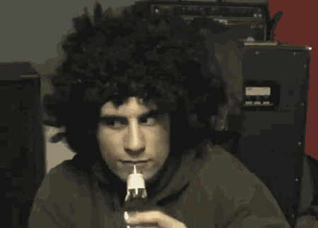 a man wearing an afro wig drinks from a bottle