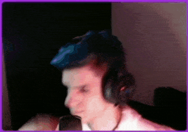 a man wearing headphones is sitting in front of a microphone in a dark room .