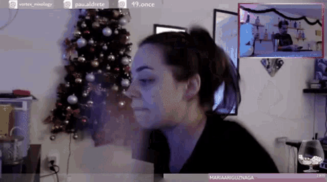 a woman is sitting in front of a christmas tree and a screen that says 49.once on it