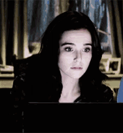 a woman is sitting in front of a computer screen looking at it .
