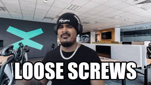 a man wearing headphones and a beanie says loose screws in an office