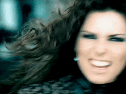a close up of a woman 's face with her hair blowing in the wind and smiling .