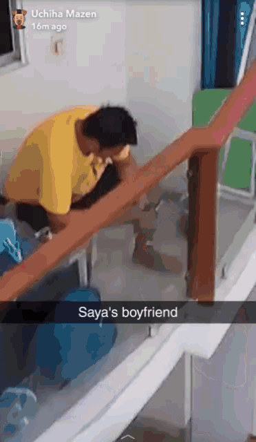a man in a yellow shirt is kneeling down in a room with the words saya 's boyfriend below him