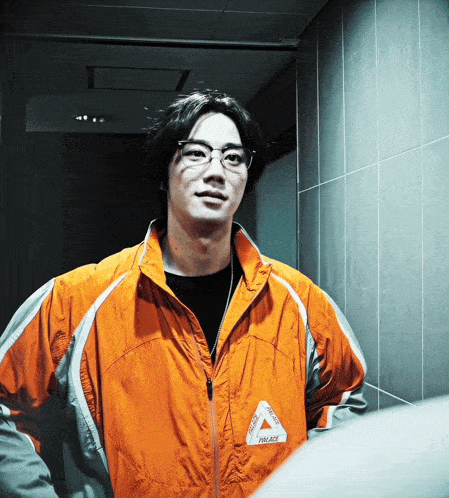 a man wearing glasses and an orange jacket that says palace on it